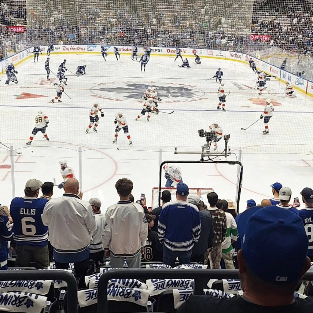 Hockey game on an ice rink with players warming up and fans watching from the stands