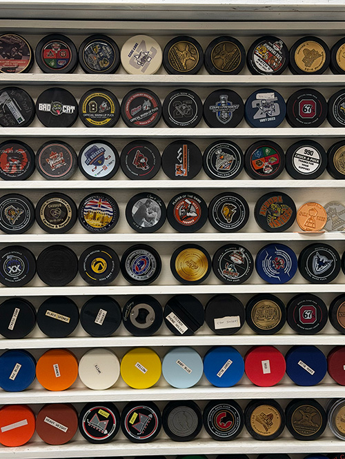 Shelves of various custom and coloured official hockey pucks